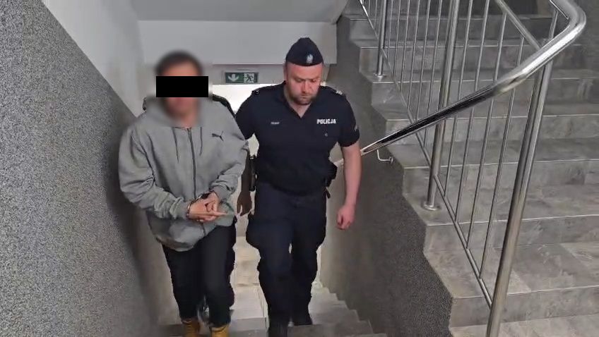 Policjanci prowadzą zatrzymanego mężczyznę.