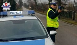 policjant z miernikiem prędkości stoi przy radiowozie