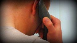 na zdjęciu mężczyzna odwrócony tyłem trzyma przy uchu słuchawkę telefonu