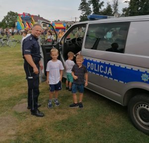 policjant i dzieci stoją obok radiowozu