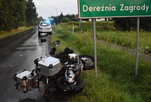 przewrócony motocykl pod tablicą z napisem Dereźnia Zagrody, w tle radiowóz