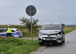 uszkodzony samochód na poboczu drogi, w tle policjantka stoi przy radiowozie