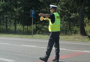 policjant stoi na drodze z tarczą do zatrzymania