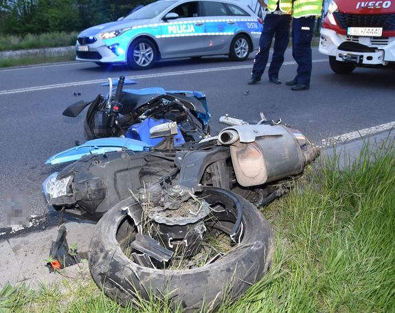 rozbity motocykl na drodze, w tle policjanci, radiowóz i wóz strażacki