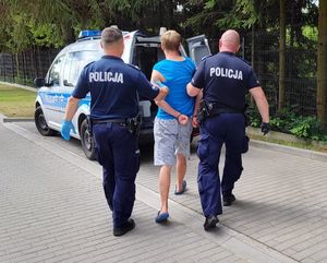 policjanci prowadzą zatrzymanego mężczyznę