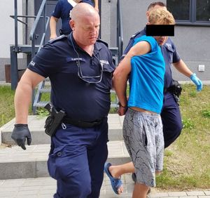 policjanci prowadzą zatrzymanego 33 latka