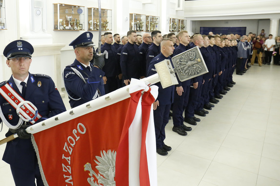 policjant ze sztandarem KWP w Lublinie w tle pododdział nowych policjantów