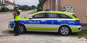 policjant mierzący prędkość stoi obok radiowozu