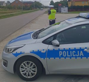 radiowóz i policjant mierzący prędkość i jadący w tle samochód