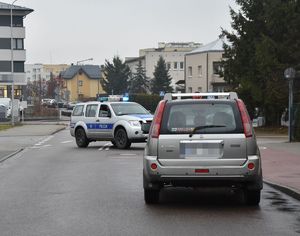 samochód Nissan stoi na ulicy, a za nim radiowóz