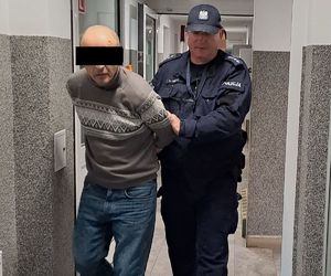 policjant prowadzi zatrzymanego po komendzie