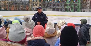 policjant i dzieci stoją przy lodowisku