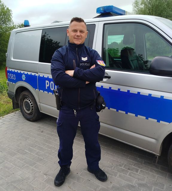 policjant stoi przy radiowozie
