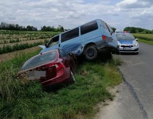 dwa uszkodzone samochody w rowie, w tle radiowóz