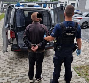 policjant prowadzi zatrzymanego do radiowozu