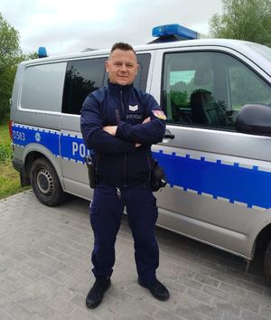 policjant stoi przy radiowozie