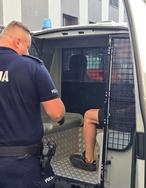 zatrzymany mężczyzna siedzi w radiowozie, umundurowany policjant zamyka drzwi radiowozu