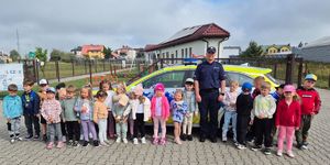 policjant z dziećmi stoi przed radiowozem