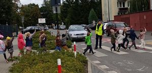 policjantka uczy dzieci jak prawidłowo przechodzić po pasach
