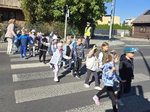 dzieci przechodzą przez przejście, w tle stoi policjant