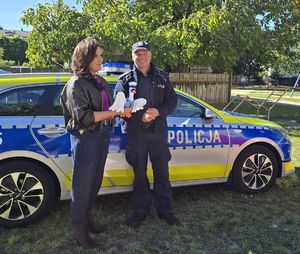 policjant wręcza dyrektorce przedszkola odblaskową maskotkę