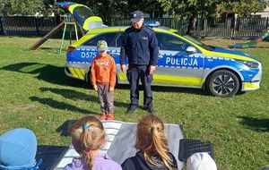 policjant i dziecko prezentują jak prawidłowo przechodzić przez przejście