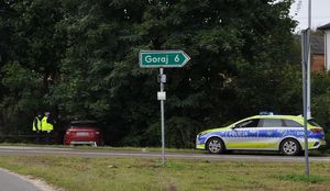 policjanci stoją przy uszkodzonym samochodzie, obok na drodze stoi radiowóz