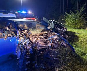 dwa uszkodzone pojazdy na poboczu drogi, w tle samochód straży pożarnej