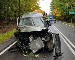 uszkodzony samochód na drodze, w tle radiowóz policyjny