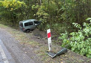 uszkodzony samochód na drodze, w tle radiowóz policyjny