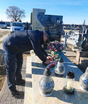 policjant kładzie wiązankę na grobie