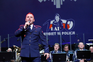 Policjant w mundurze śpiewa z okazji setnej rocznicy powołania Policji Kobiecej.