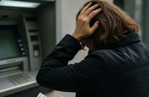 kobieta trzymająca się z głowę stoi przy bankomacie