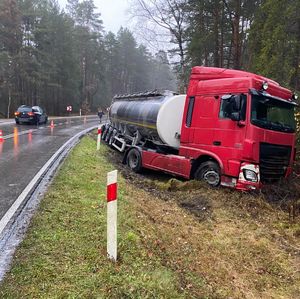 cysterna w przydrożnym rowie, w tle mężczyzna i jadący drogą samochód