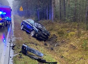 samochód osobowy w rowie, obok na jezdni radiowóz policyjny i wóz strażacki