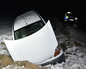 uszkodzony pojazd w przydrożnym rowie, w tle radiowóz