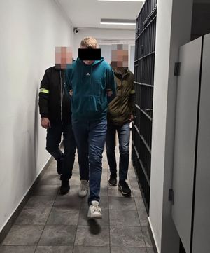 policjanci prowadzą zatrzymanego mężczyznę