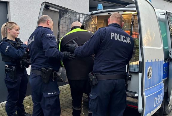 policjanci umieszczają zatrzymanego w radiowozie