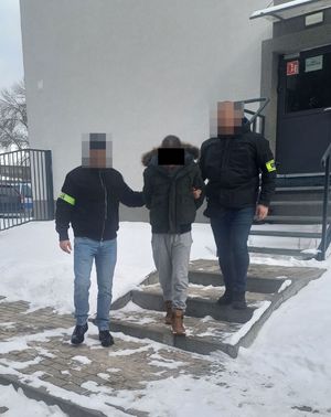 Policjanci prowadzą osobę zatrzymaną