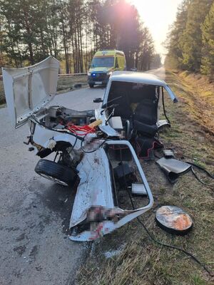 uszkodzony samochód na drodze, w tle karetka