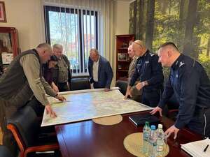uczestnicy spotkania w Nadleśnictwie Zwierzyniec pochyleni nad stołem na którym rozłożona jest mapa