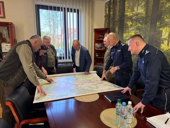 uczestnicy spotkania w Nadleśnictwie Zwierzyniec pochyleni nad stołem na którym rozłożona jest mapa