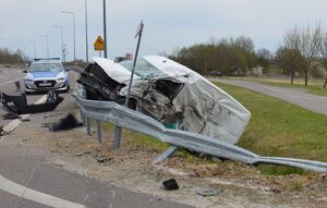 uszkodzony samochód poza drogą, w tle na jezdni radiowóz
