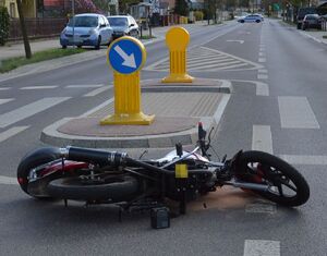 motorower leżący na jezdni, w dalszym planie radiowóz