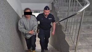 Policjanci prowadzą zatrzymanego mężczyznę.