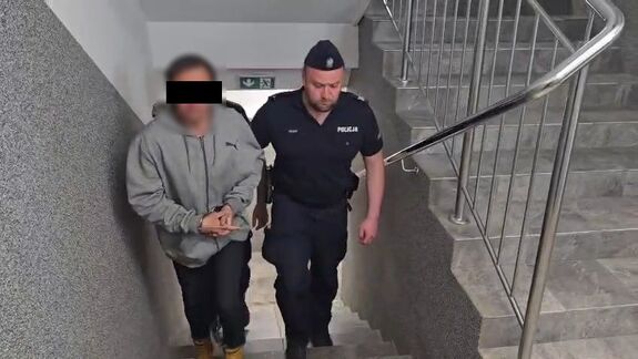 Policjanci prowadzą zatrzymanego mężczyznę.