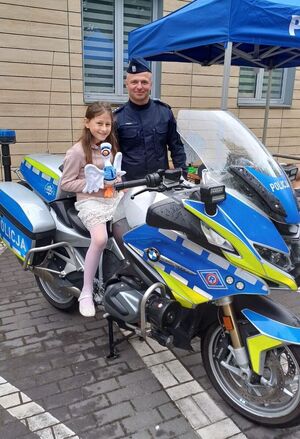 policjant i dziewczynka siedząca na motocyklu pozują do zdjęcia