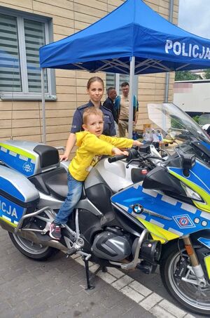 policjantka i dziecko siedzące na motocyklu pozują do zdjęcia