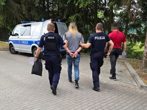policjanci prowadzą zatrzymanego do radiowozu