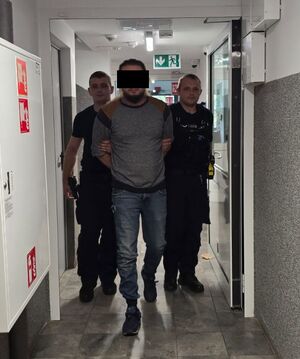policjanci prowadzą zatrzymanego mężczyznę